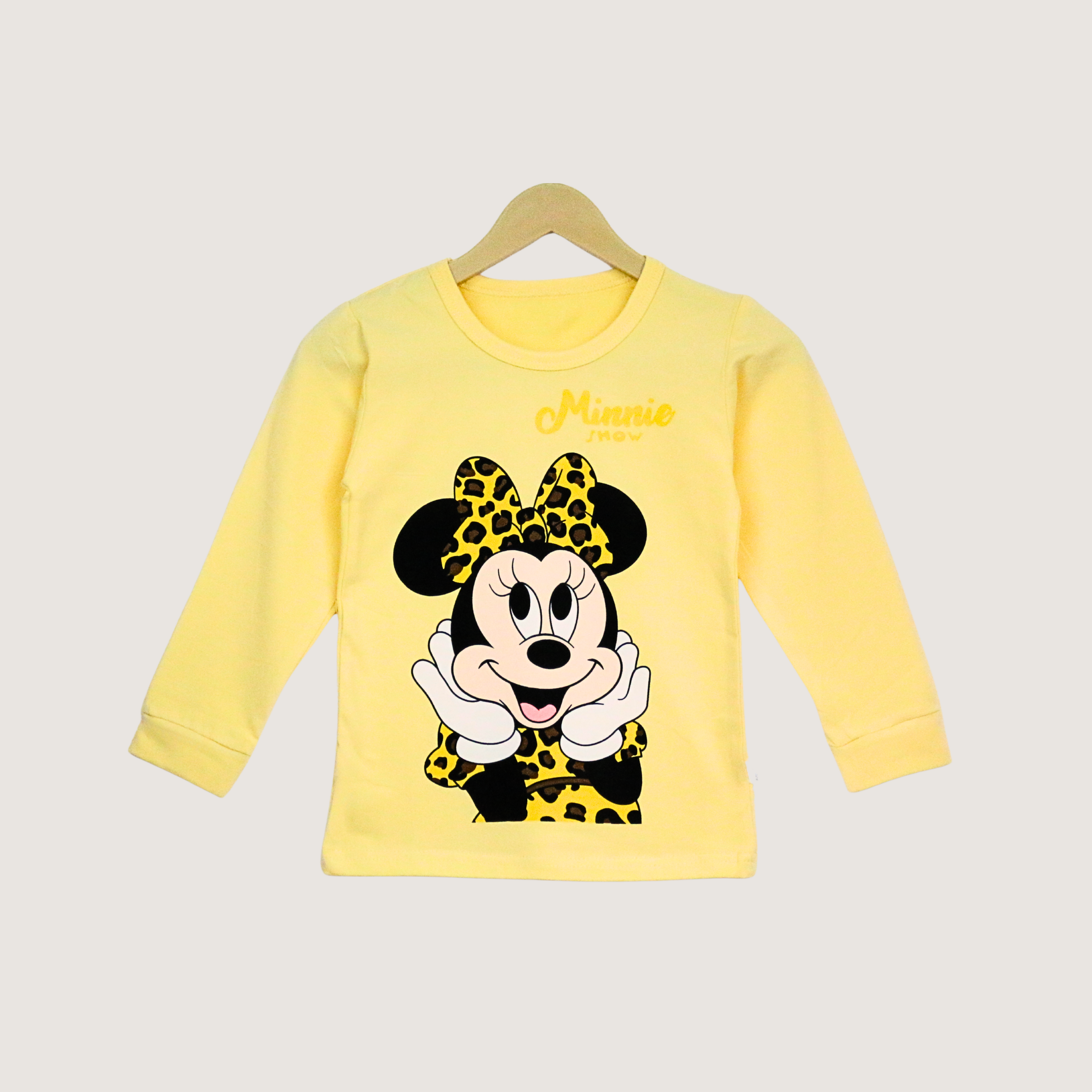 Yellow long-sleeve shirt with Minnie Mouse design on a hanger against a light gray background