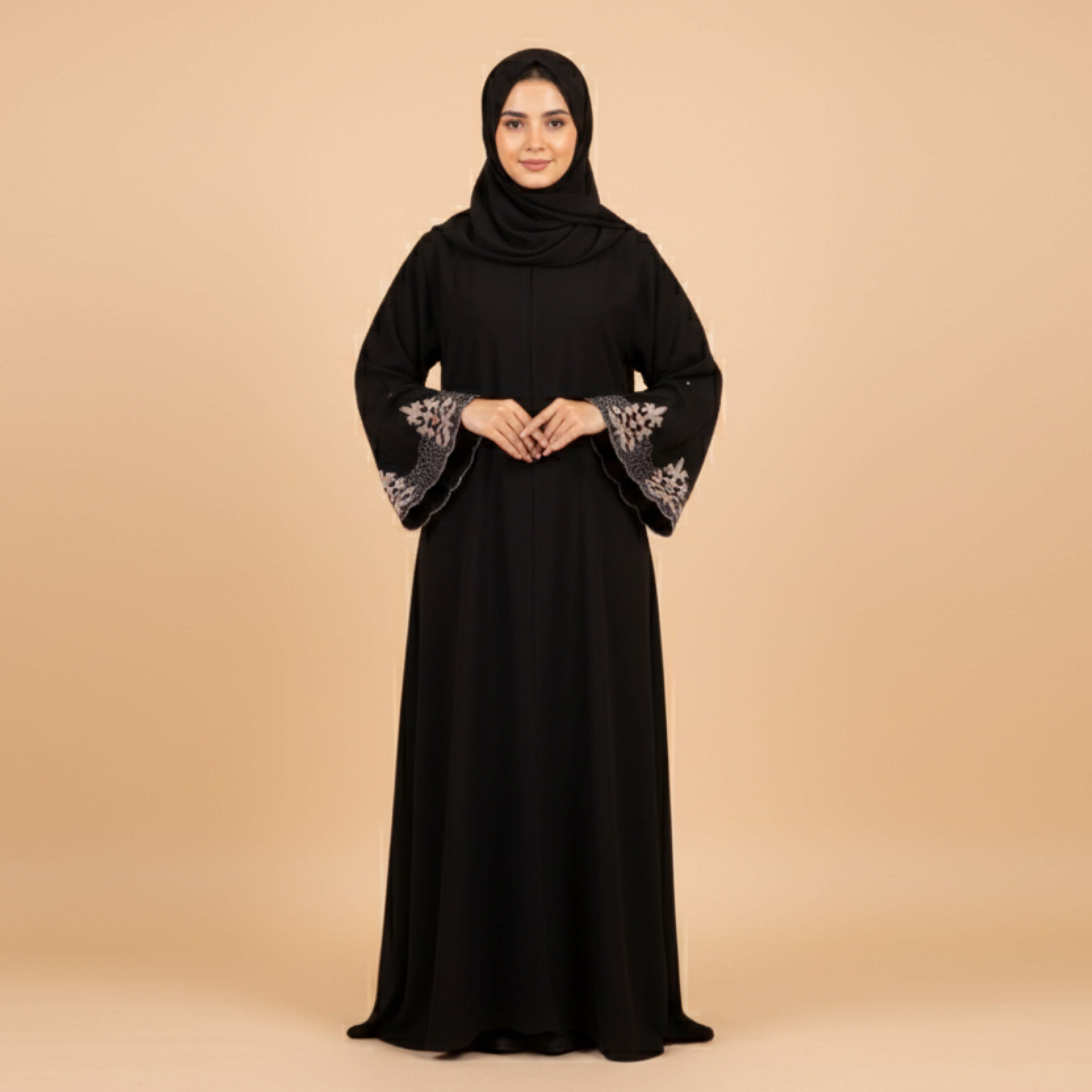 Woman wearing a black abaya with floral embroidery on a beige background