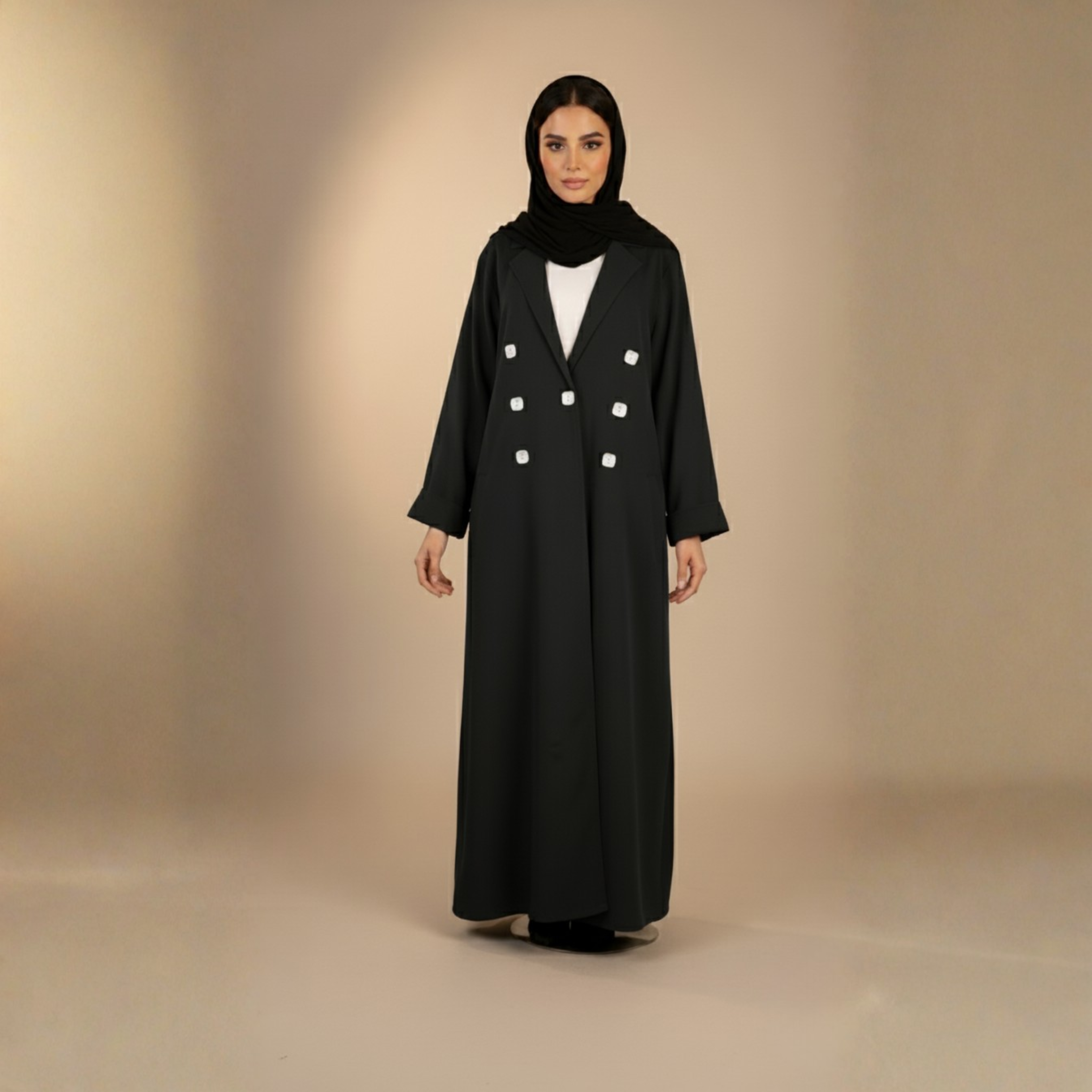 Woman wearing a black long coat with white buttons on a beige background