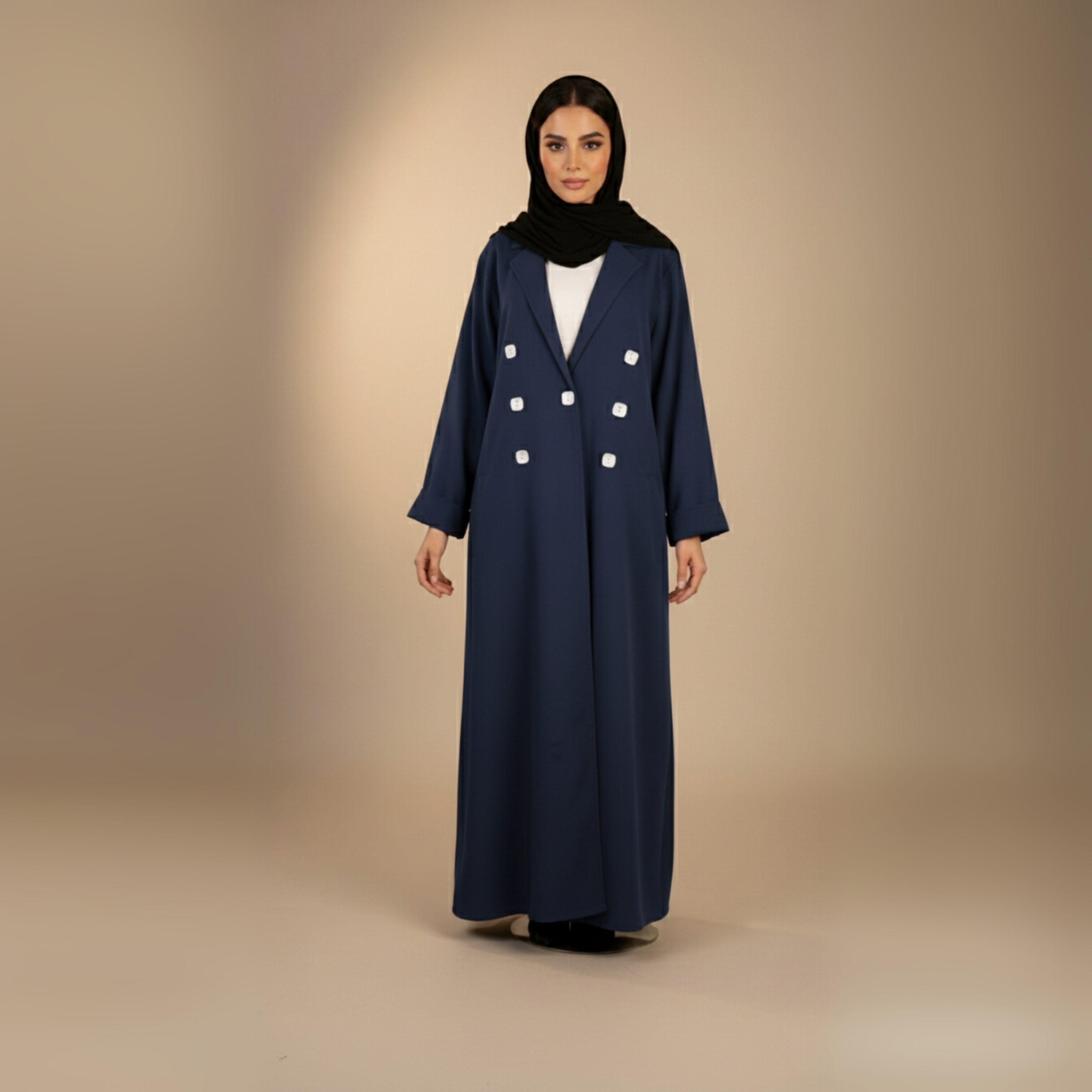 Woman wearing a long navy coat with white buttons on a beige background