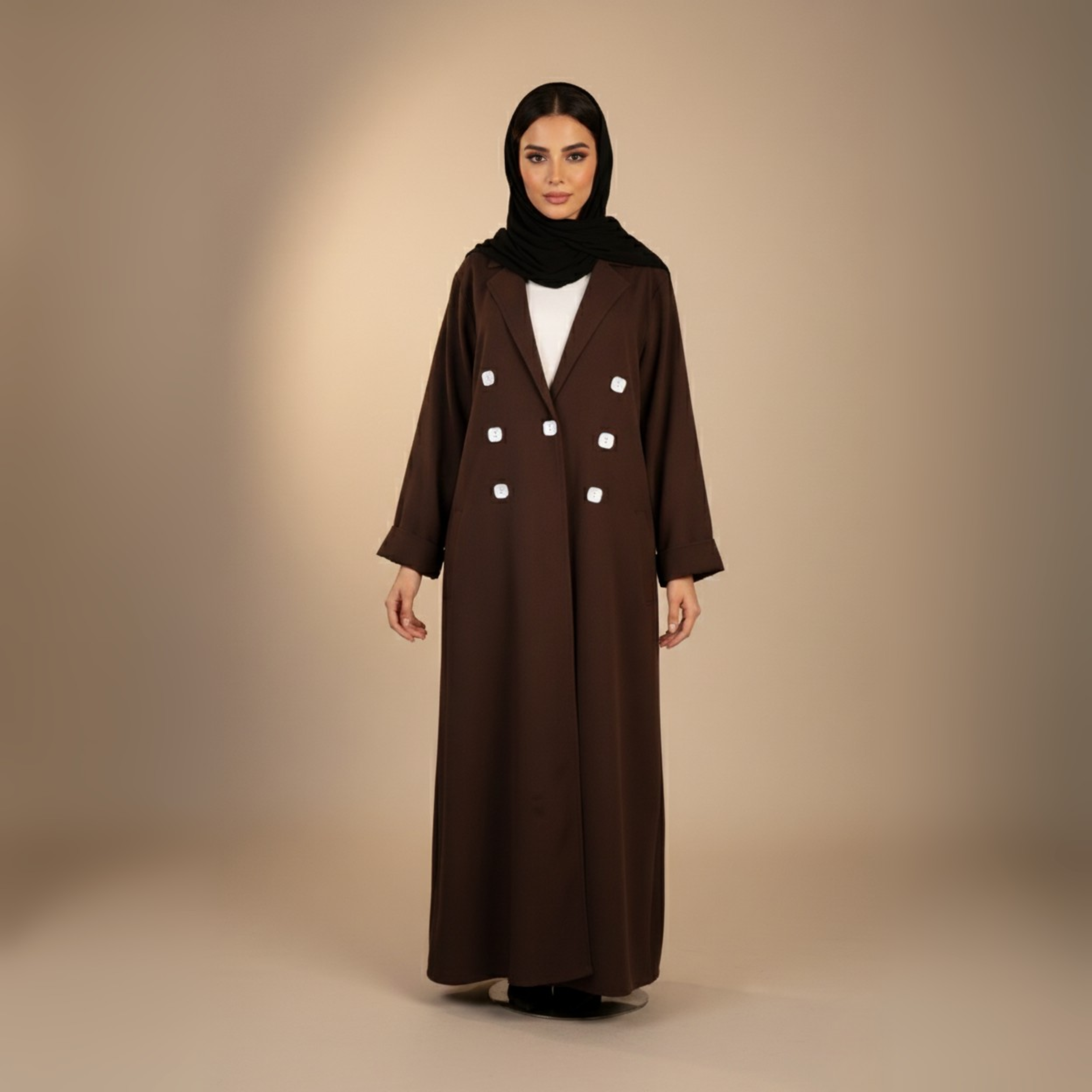 Woman wearing a brown abaya with white buttons on a beige background