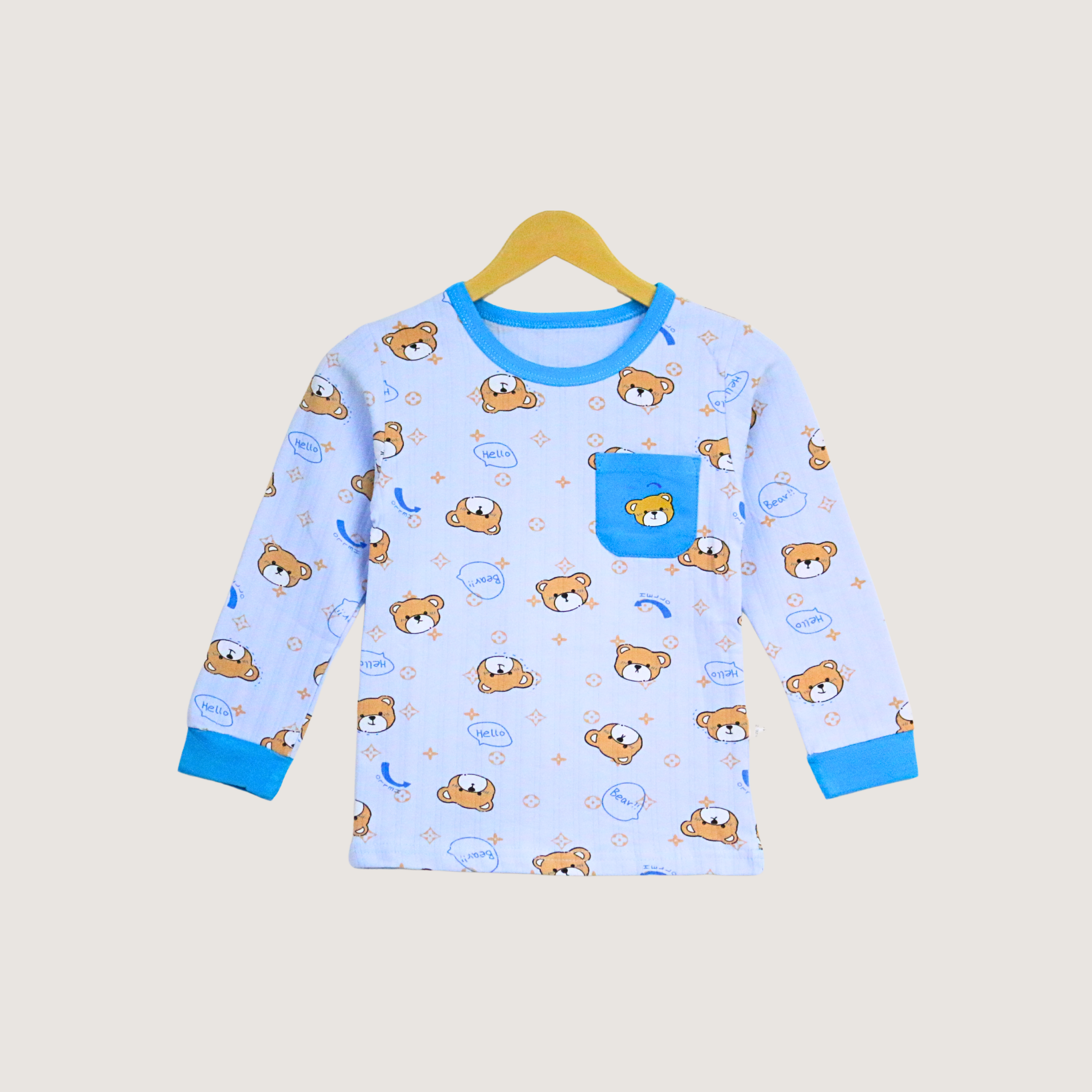 Children's blue pajama top with teddy bear pattern on a beige background