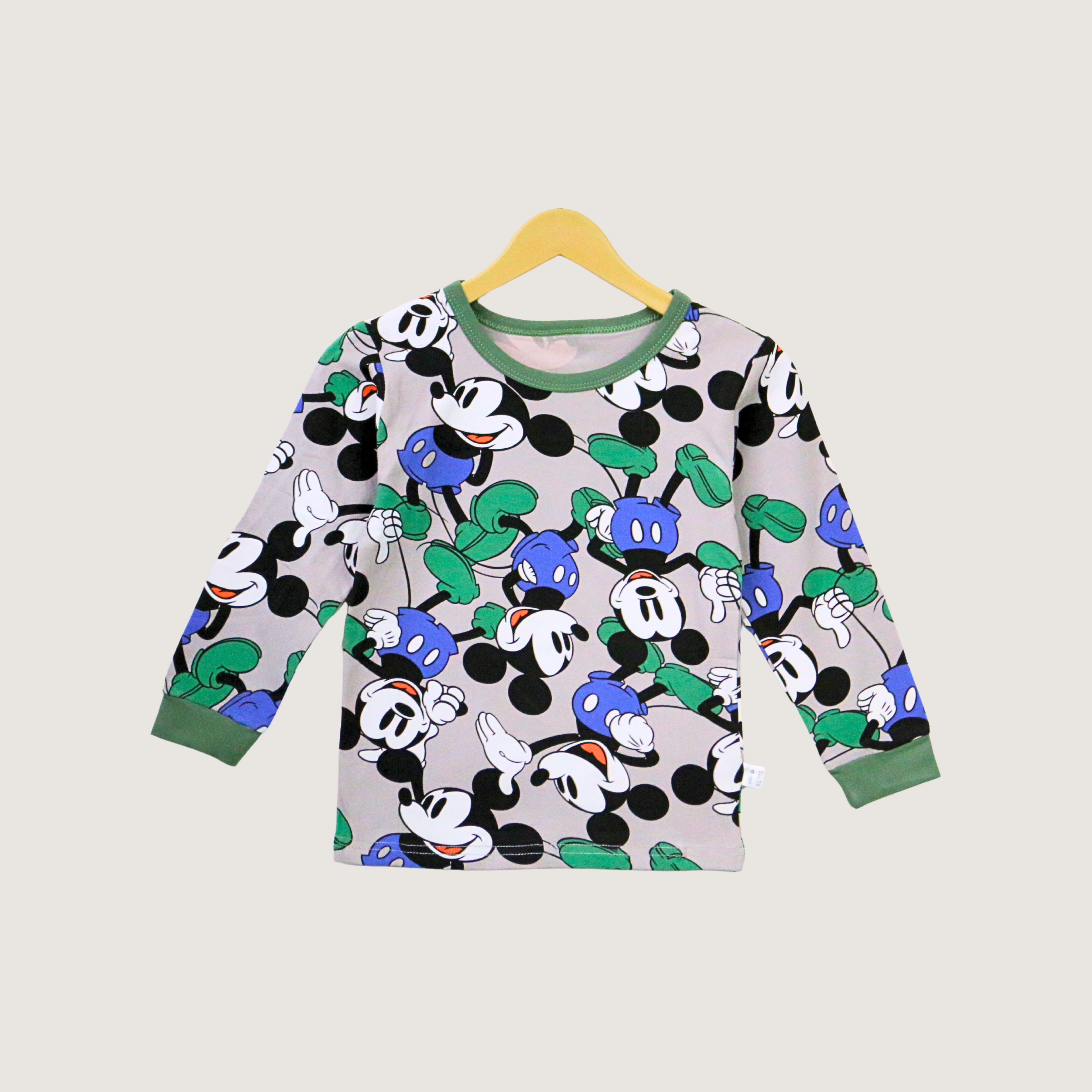 Children's long-sleeve shirt with Mickey Mouse pattern on a hanger against a light gray background