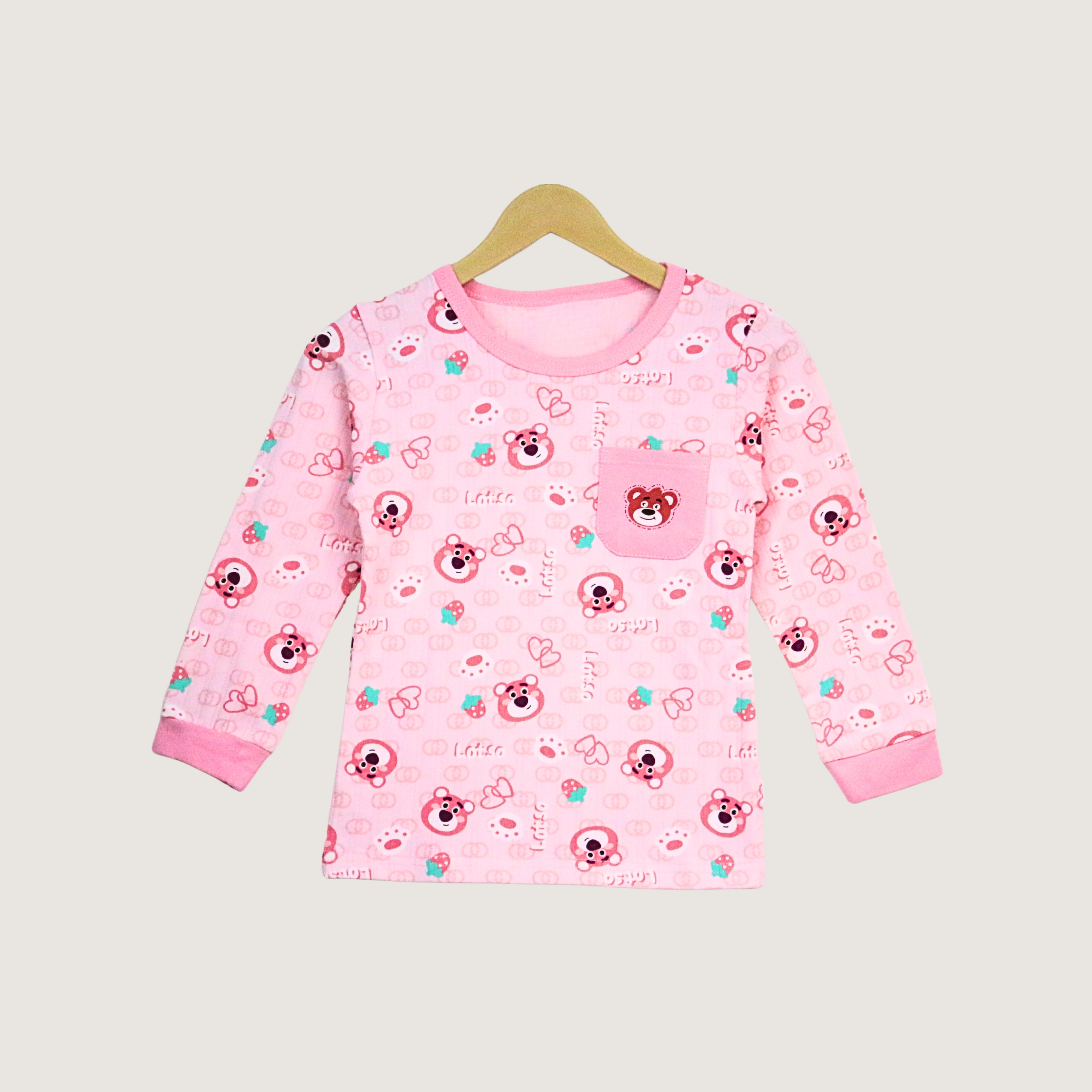 Pink children's dress with teddy bear pattern on a hanger against a light gray background