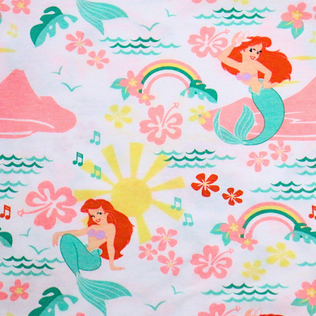 Colorful fabric pattern with mermaids, flowers, and rainbows on a light background