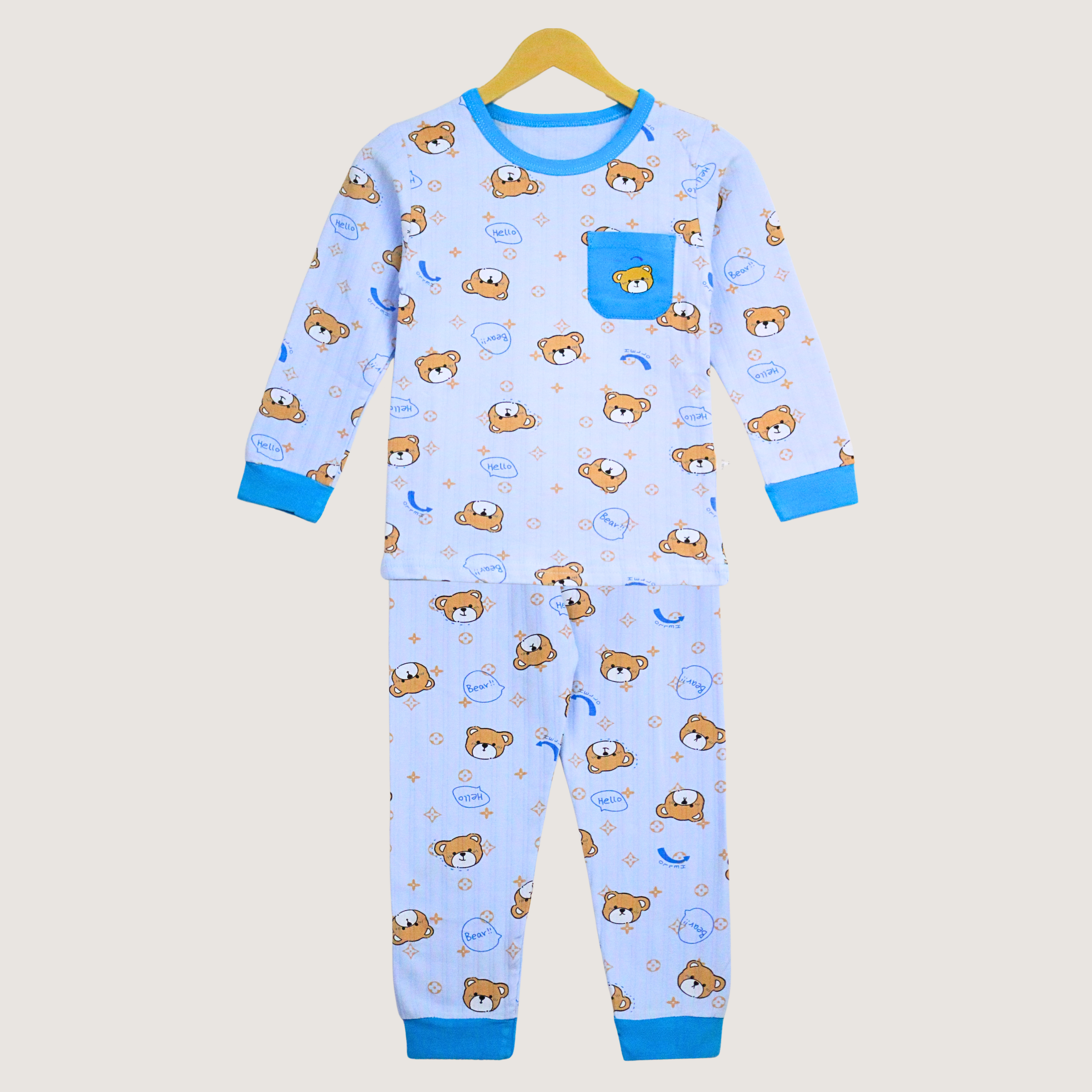 Children's pajama set with bear pattern on a hanger against a beige background