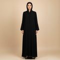 Woman wearing a black abaya against a beige background