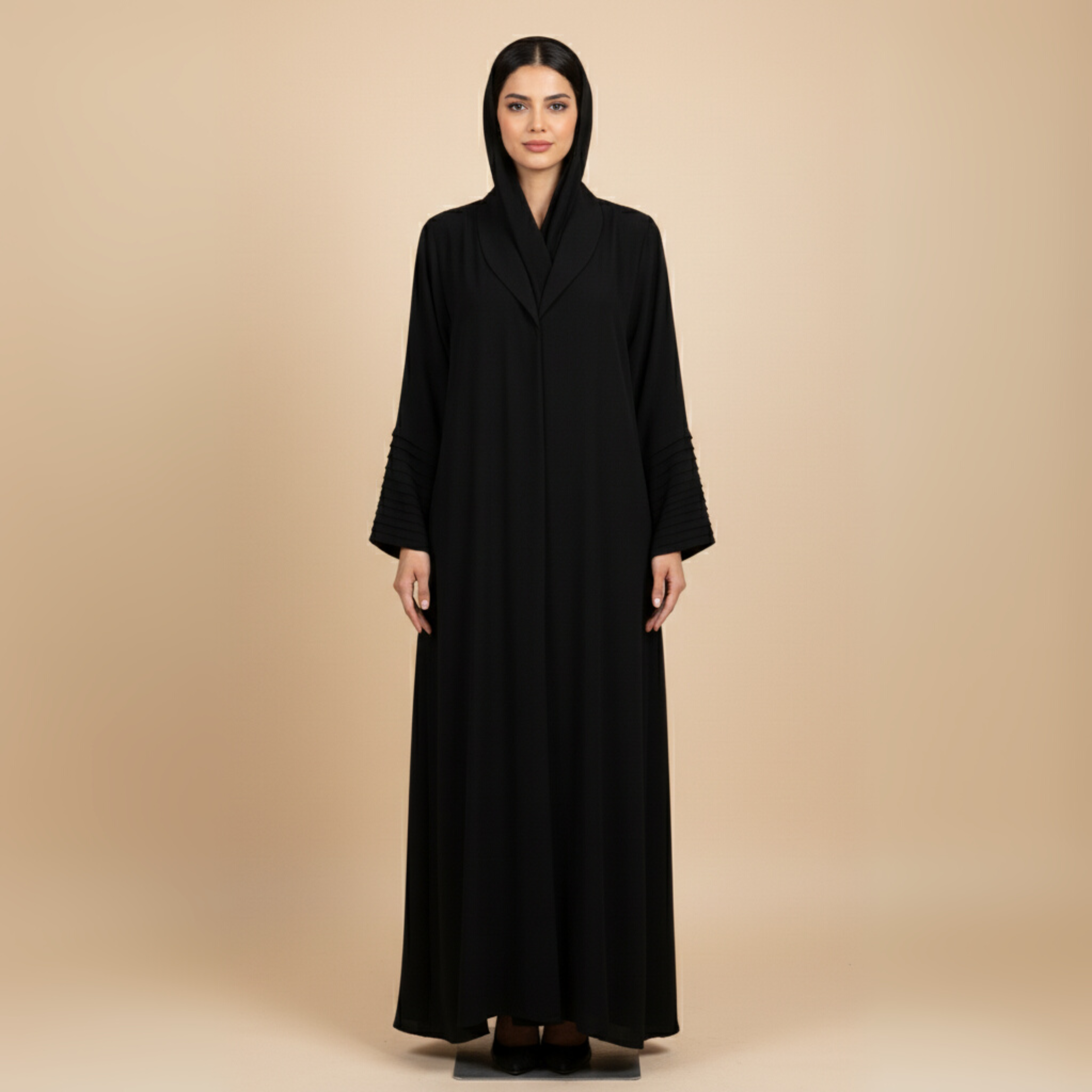 Woman wearing a black abaya against a beige background
