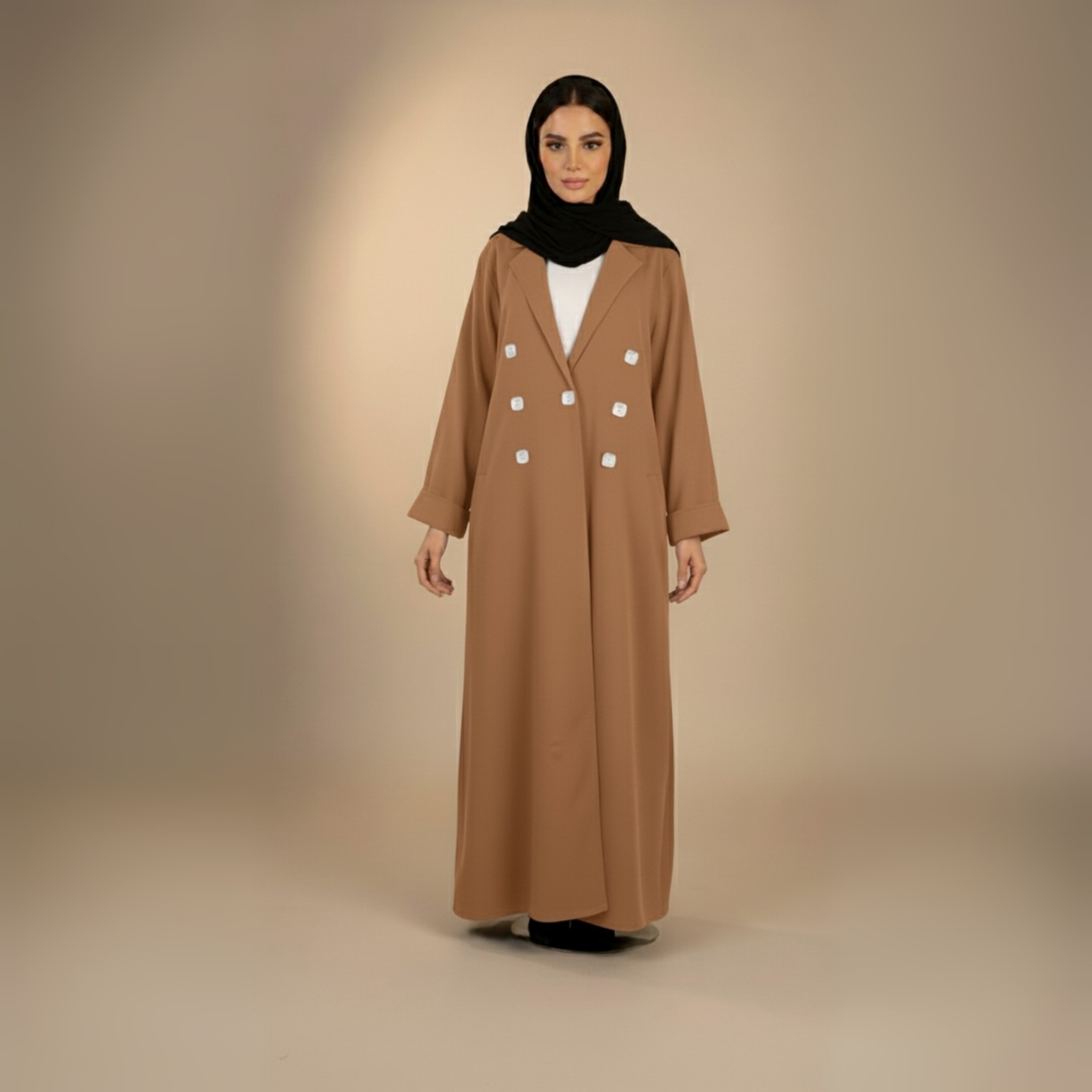 Woman wearing a long brown coat and black hijab on a beige background